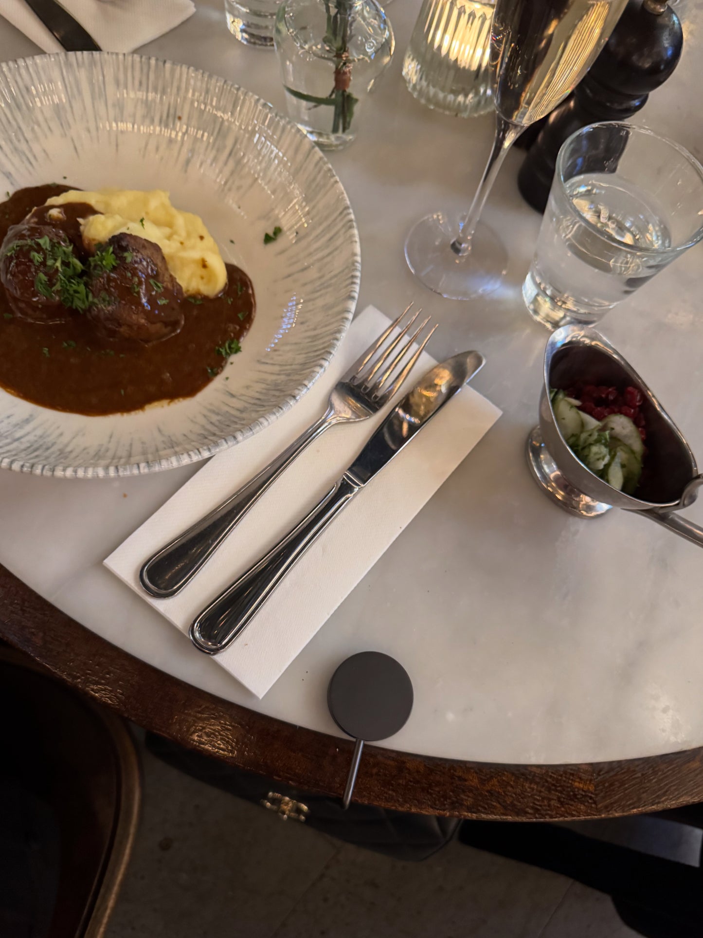 Bag hook by A’VERIE STUDIOS holding a designer handbag securely on any table.